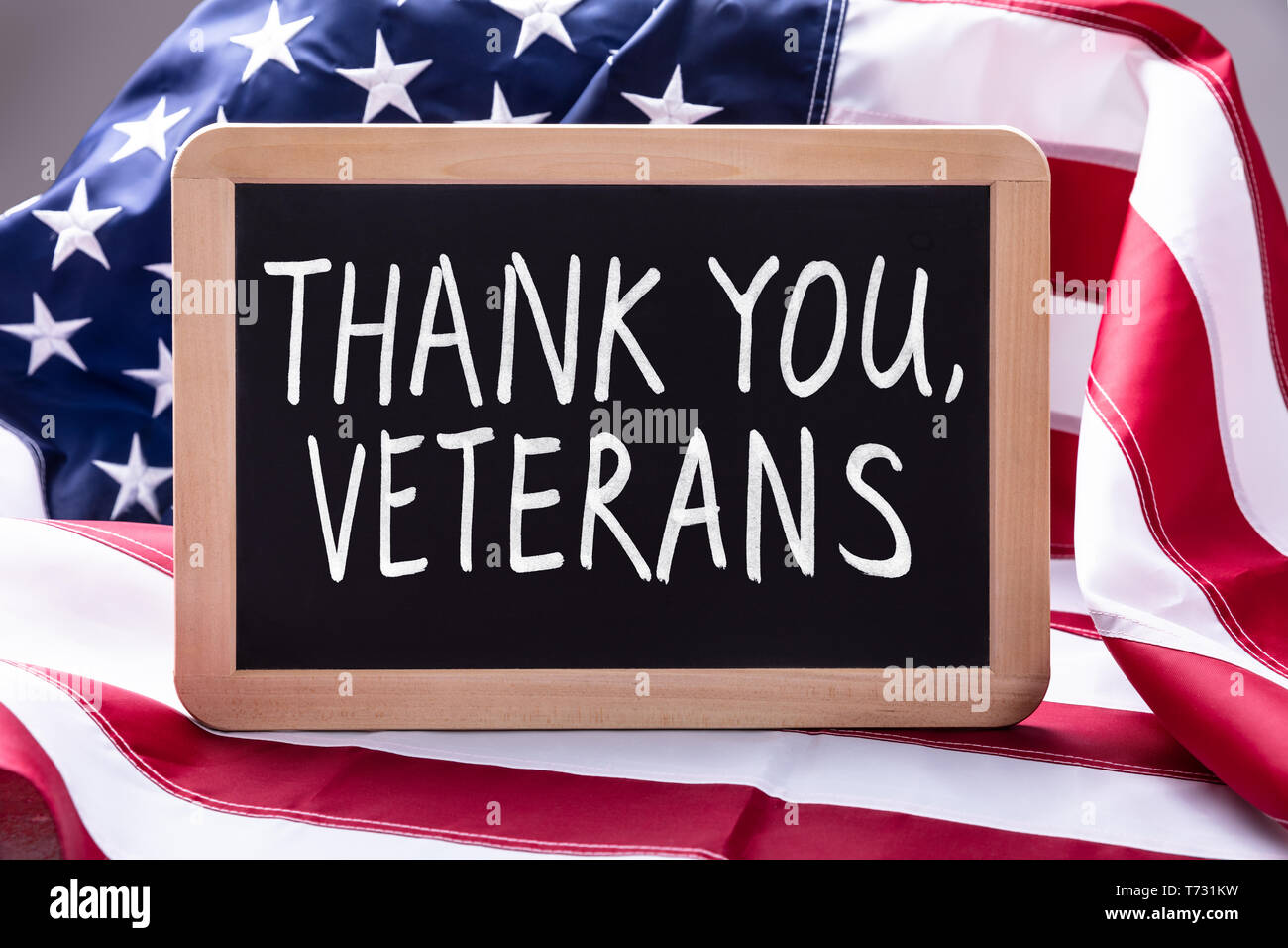 Top View Of Thank You Veterans Text Written On Slate Over American Flag Stock Photo