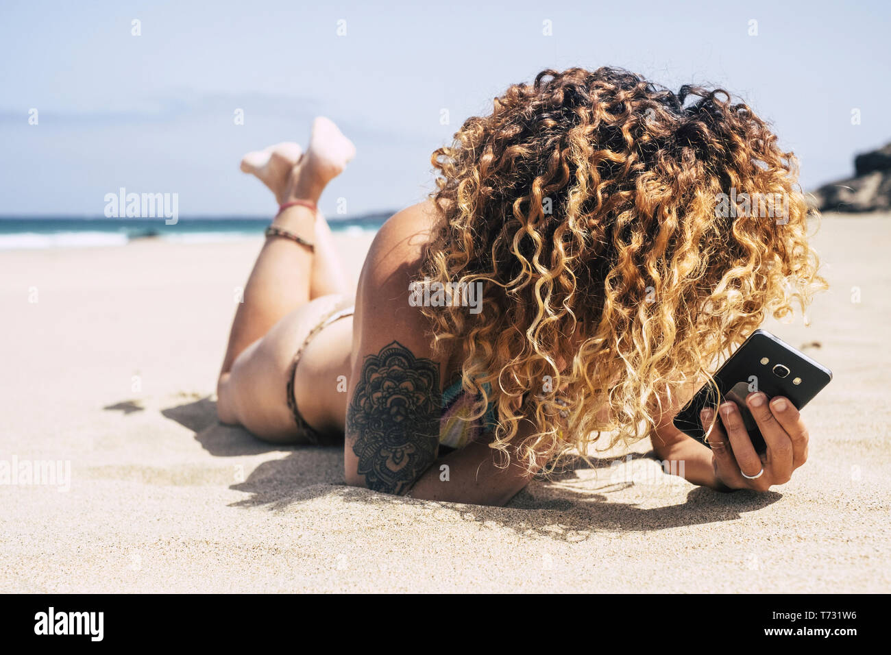 Unrecognizable bikini attractive young woman enjoying the summer holiday vacation at the beach laying down on the sand to take a wonderful sunbath wit Stock Photo