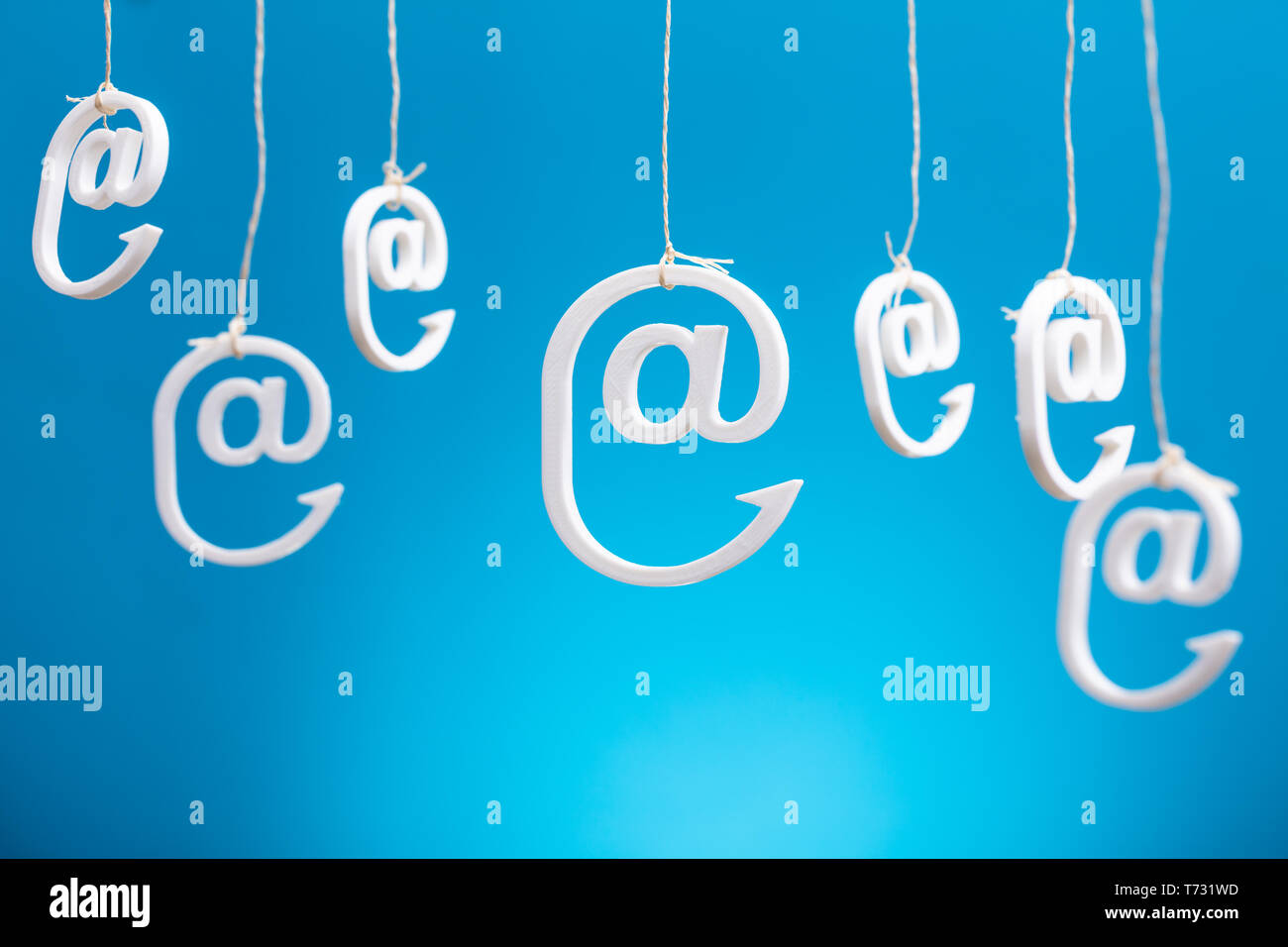 Email Icons Hanging By Strings Against Blue Backdrop Stock Photo