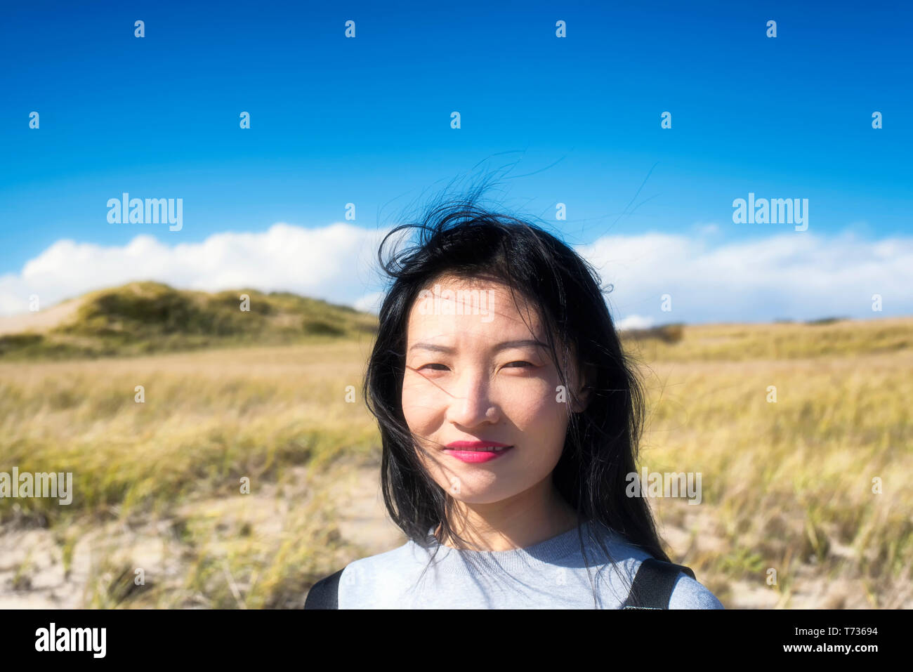 A chinese woman outside on a sunny windy day on the cape cod national seashore in Truro Massachusetts. Stock Photo