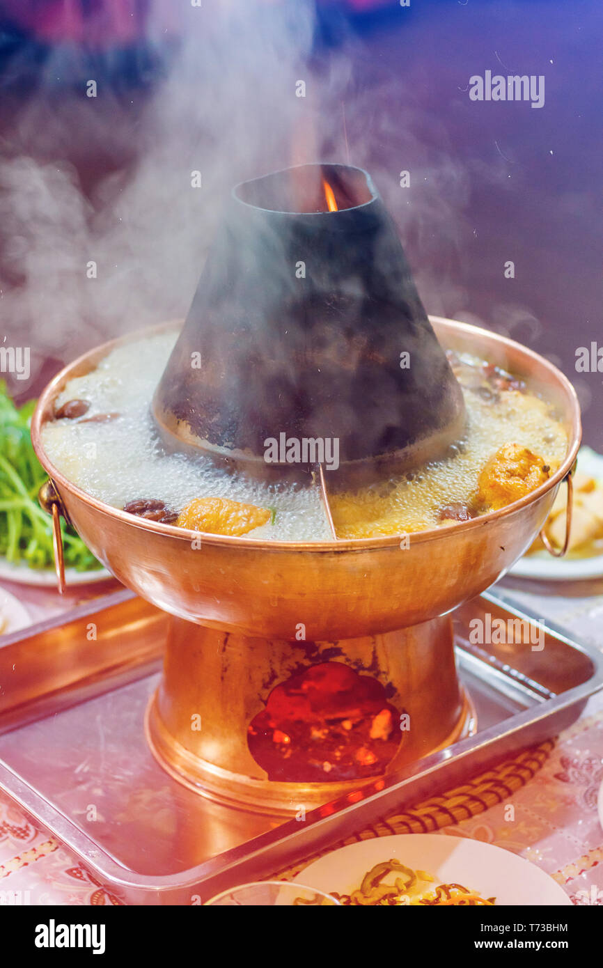 Chinese traditional hot pot on an open fire with large steam Stock