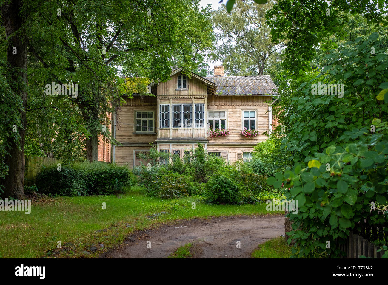 Traditional wooden house of an ancient suburb, set in a luxuriant garden, taken during an overcast morning, Riga, Latvia Stock Photo