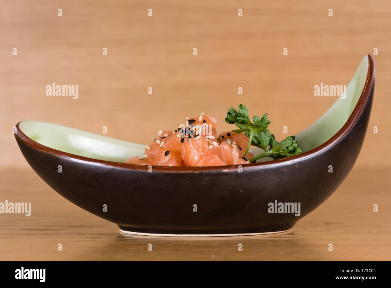 fresh salmon tartare with black and white sesame, served on a boat-shaped plate Stock Photo