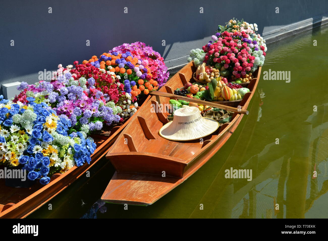 Milan/Italy - June 30, 2015: Two Thai wooden traditional boats for floating market filled with flowers anchored at Thailand Milano EXPO 2015 pavilion. Stock Photo