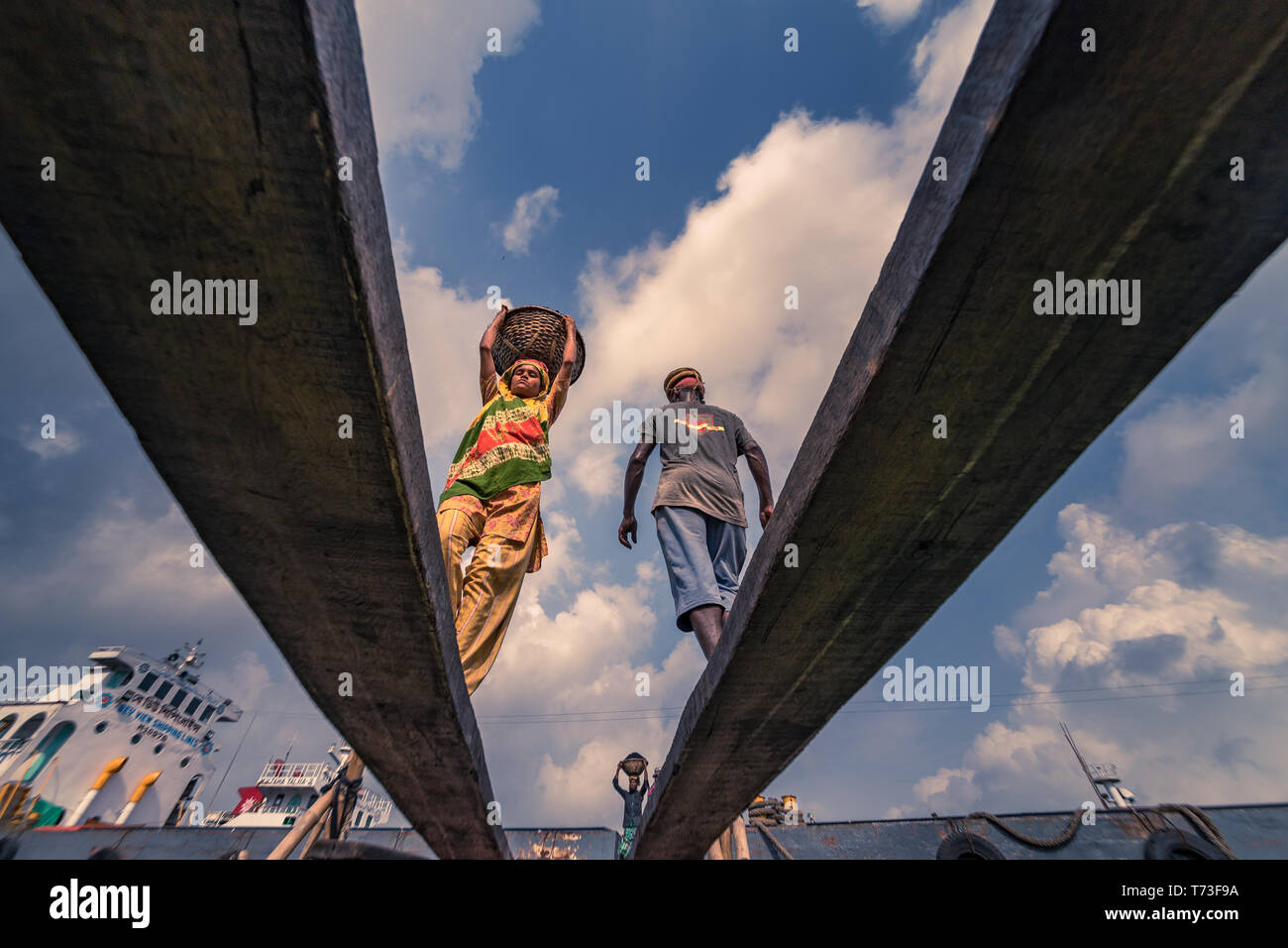 Male & Female dock workers are seen as they unload coal with bamboo baskets from ferries at Buriganga river port in Dhaka, Bangladesh. Stock Photo