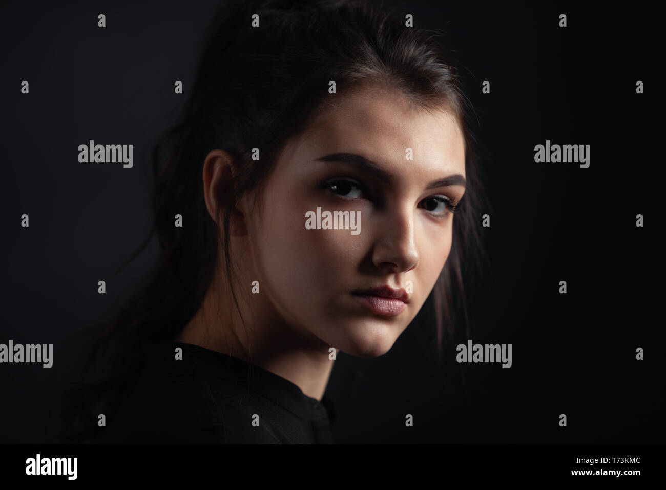 Dramatic portrait of a beautiful lonely girl on a dark background in studio Stock Photo