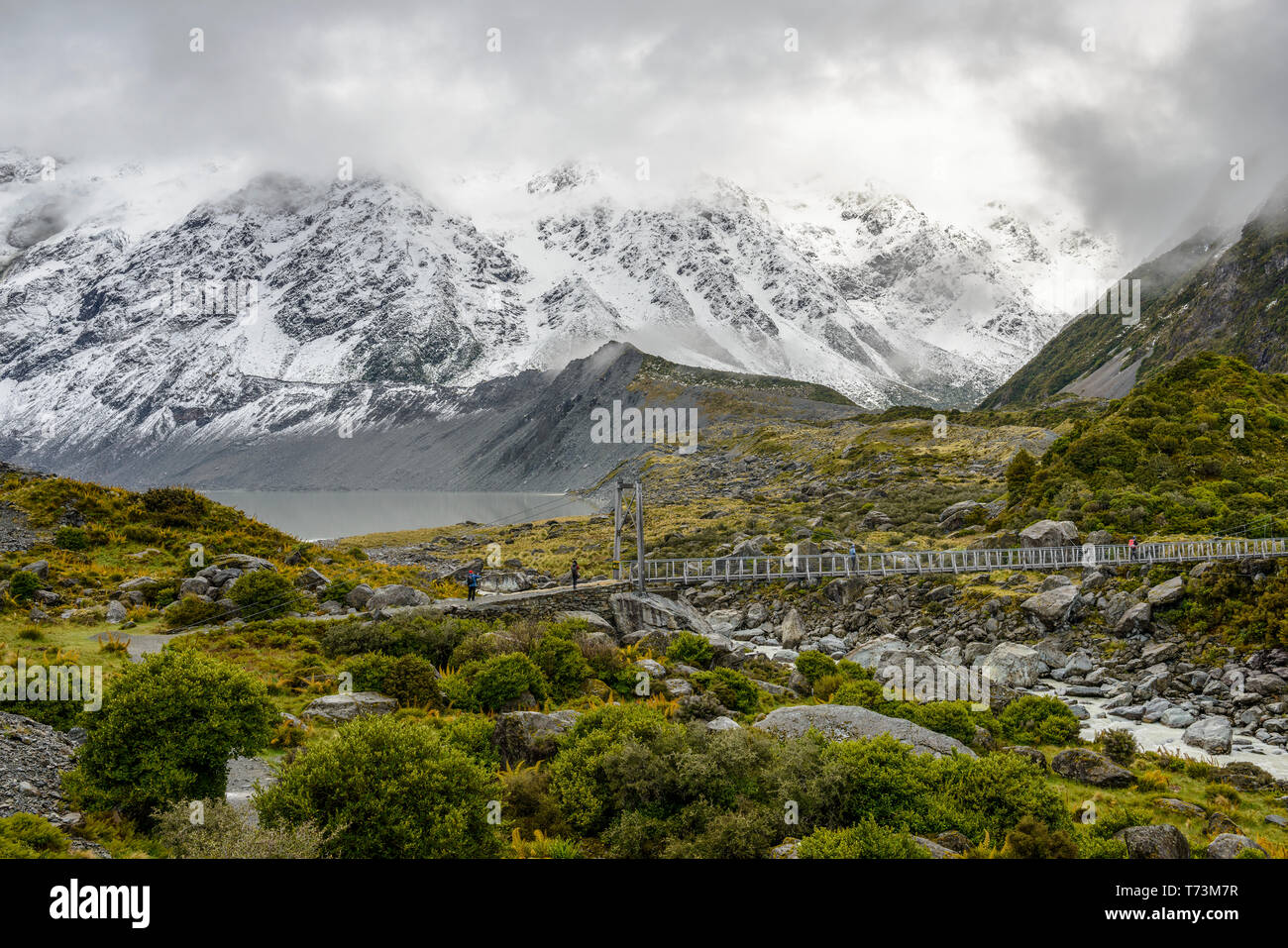 Snowy mountains and hanging bridge along the Hooker Valley Track, Mount Cook National Park; South Island, New Zealand Stock Photo