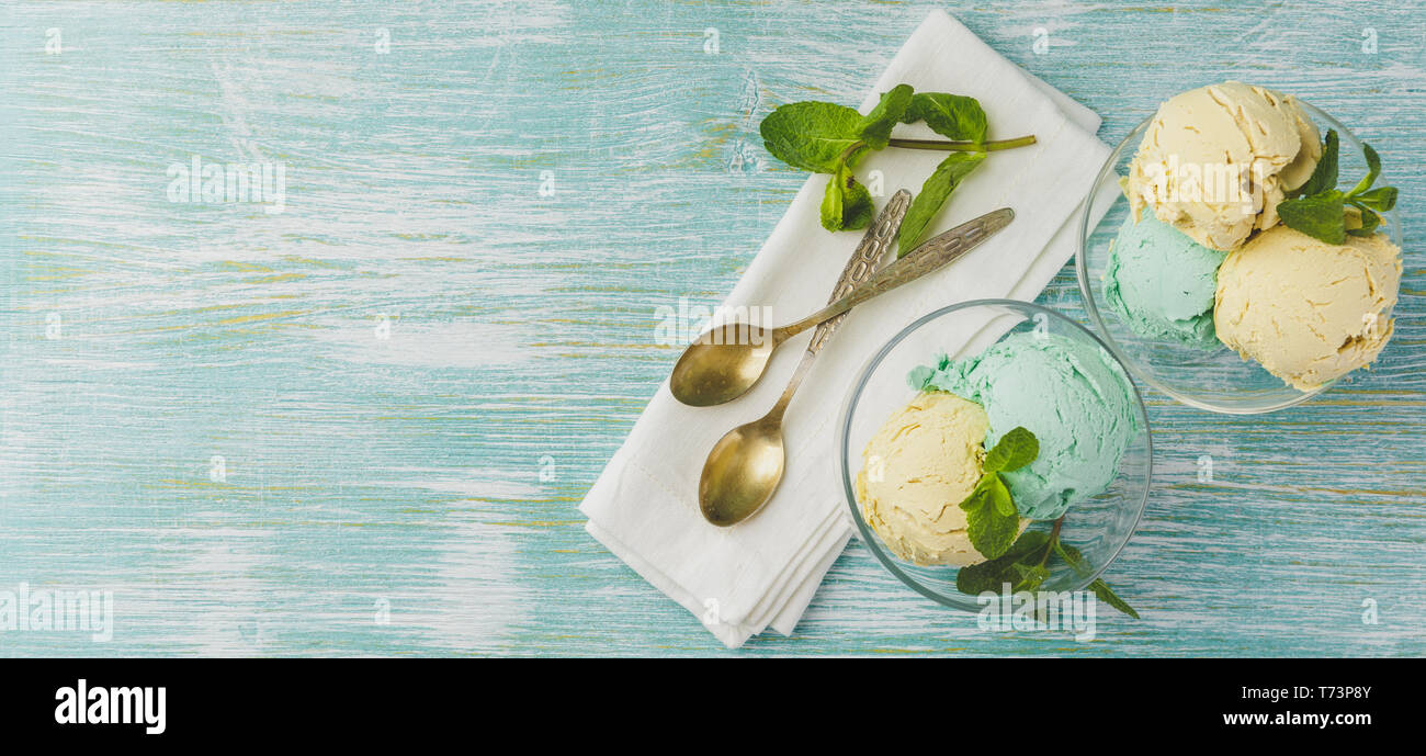 Mint and lemon ice cream with mint leaves in glass bowl on green wooden ...