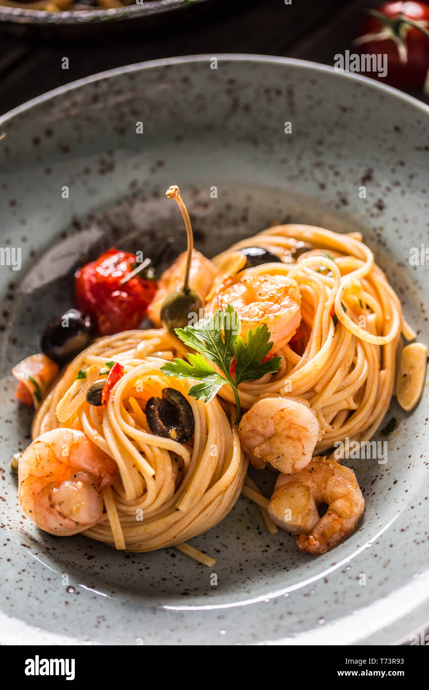 Pasta spaghetti on plate and pan with shrimp tomato sauce toatoes and herbs. Italian or mediterranean cuisine. Stock Photo