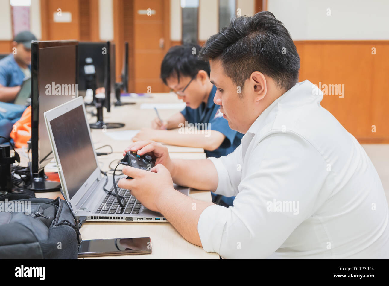 Asian University Student playing game on his laptop during a computer ...