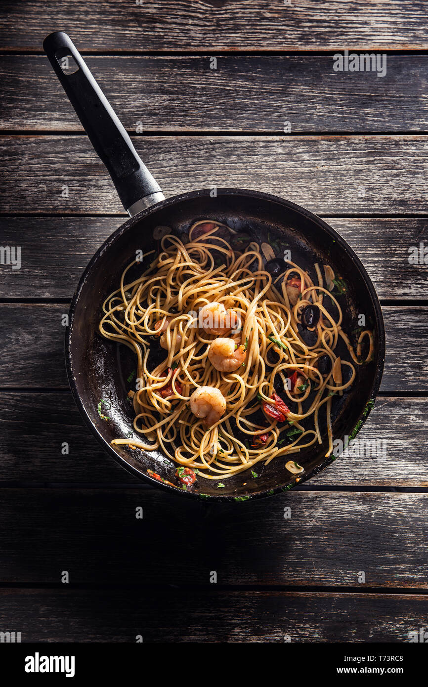 Pasta spaghetti on pan with shrimp tomato sauce toatoes and herbs. Italian or mediterranean cuisine. Stock Photo