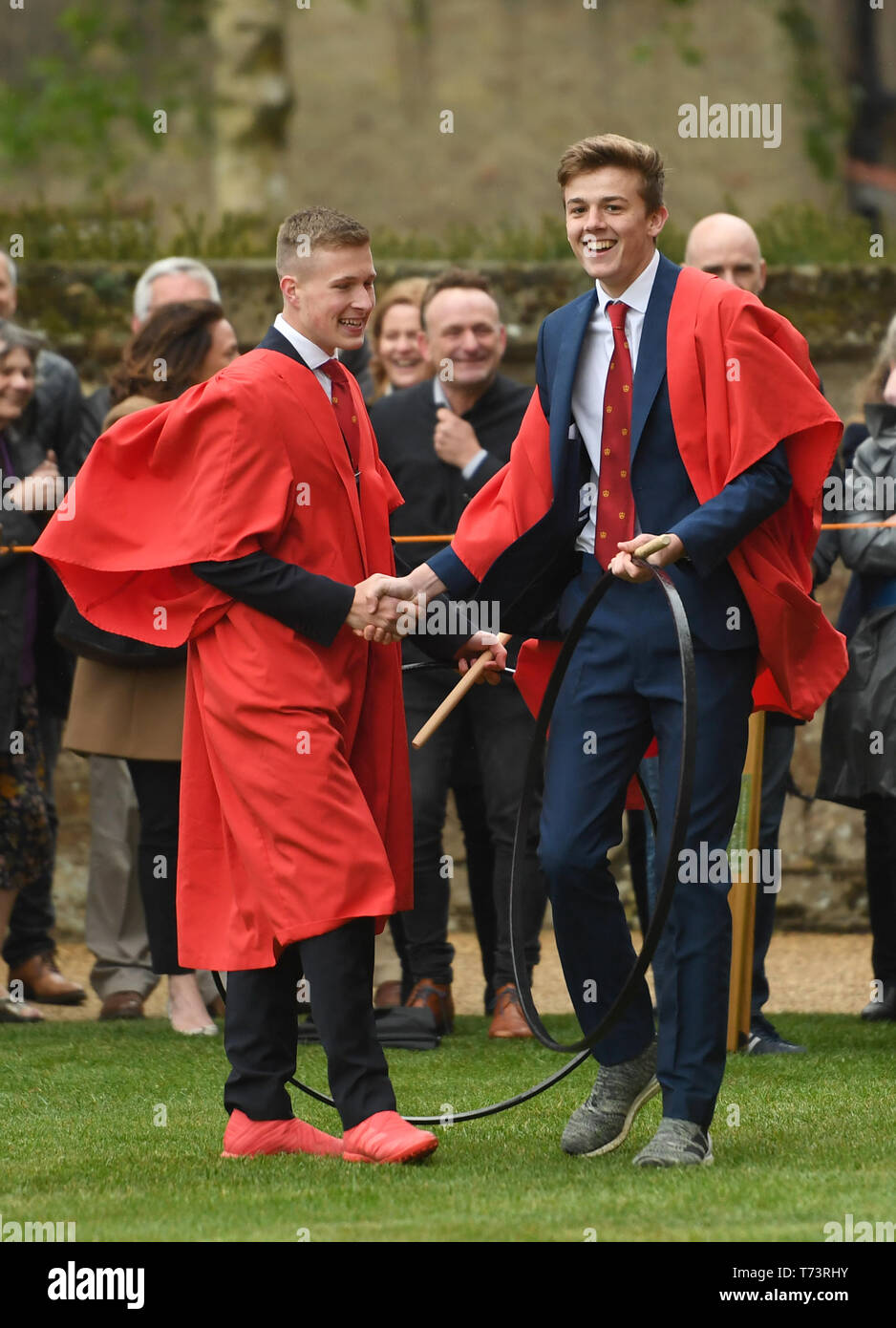 Head boy Sol Boon (right) celebrates winning the annual King's Ely Hoop Trundle on the east lawn at Ely Cathedral, to mark the re-founding of the school by King Henry VIII, in 1541. The course is a 75 yard dash to a post and back whilst bowling the hoop with a wooden stick. Stock Photo