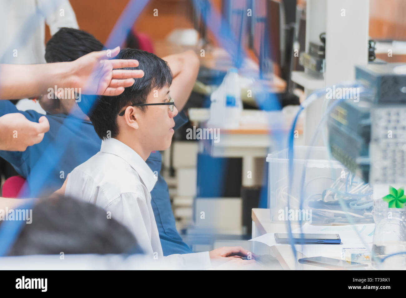 Portrait of asian university student working on computer network project in a group with server and other LAN cable in the foreground Stock Photo