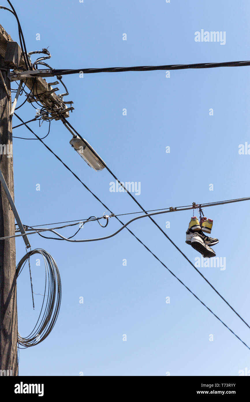 Sneakers hanging on the power line. Blue sky. Bad joke. Beauty photo filter  Stock Photo - Alamy