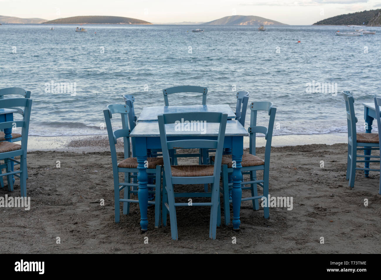 Traditional greek tavern with wooden tables on sandy beach near water waiting for tourists in Tolo, Peloponnese, Greece, vacation season is starting Stock Photo