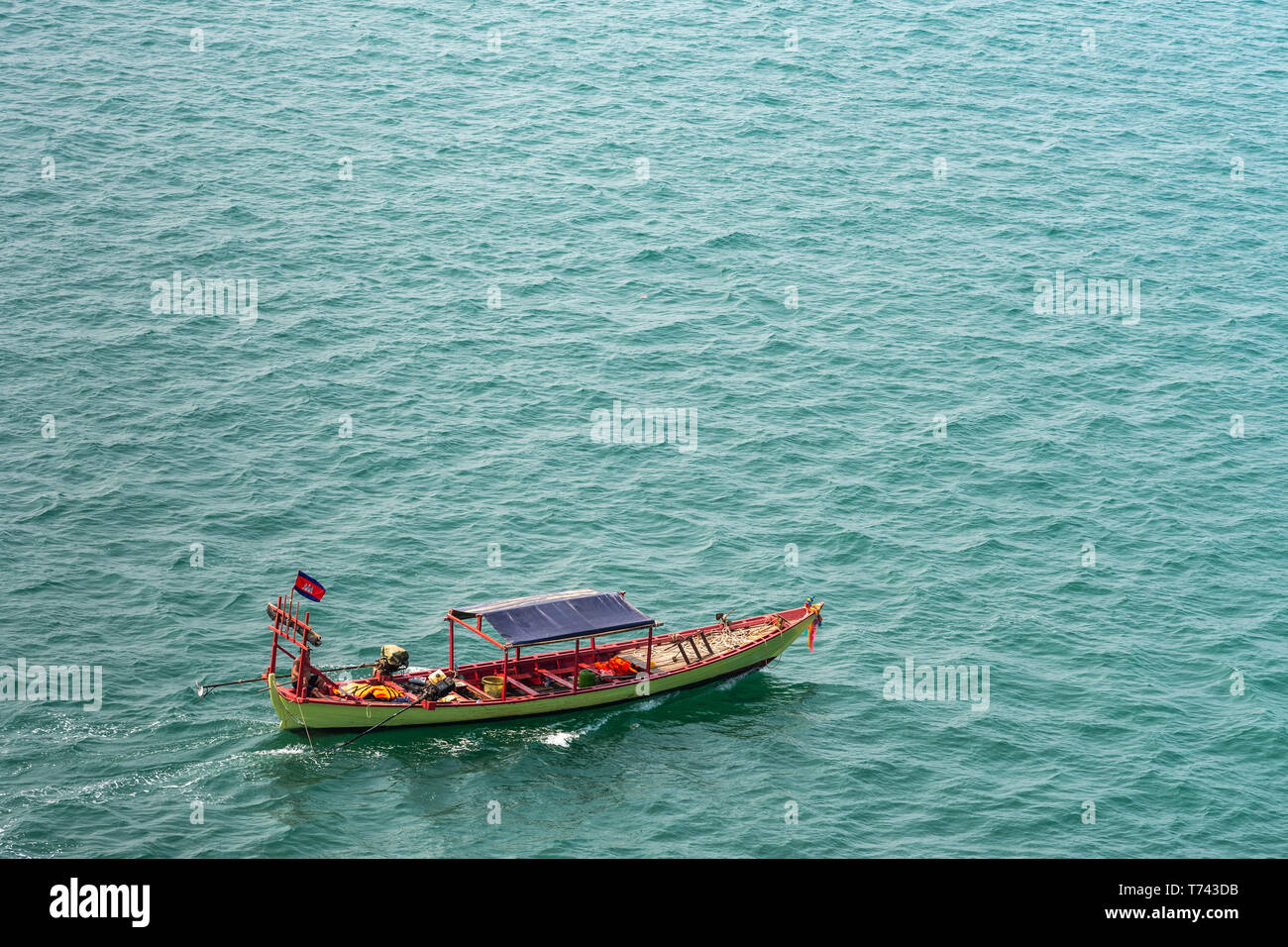 Sihanoukville, Cambodia - March 15, 2019: Small green and red fishing sloop on greenish sea water outside Sihanouk Autonomous Port. Stock Photo