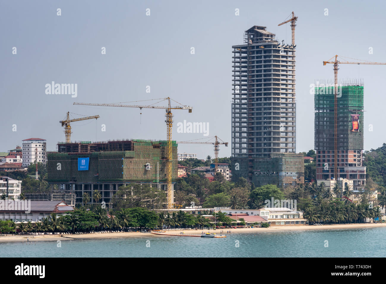 Sihanoukville, Cambodia - March 15, 2019: Shoreline turned into massive construction site of tall high rise buildings under light blue sky, yellow cra Stock Photo