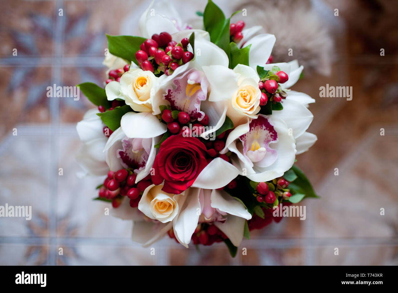 Exquisite bouquet of red and white roses with orchids, complemented by red hypericum berries Stock Photo