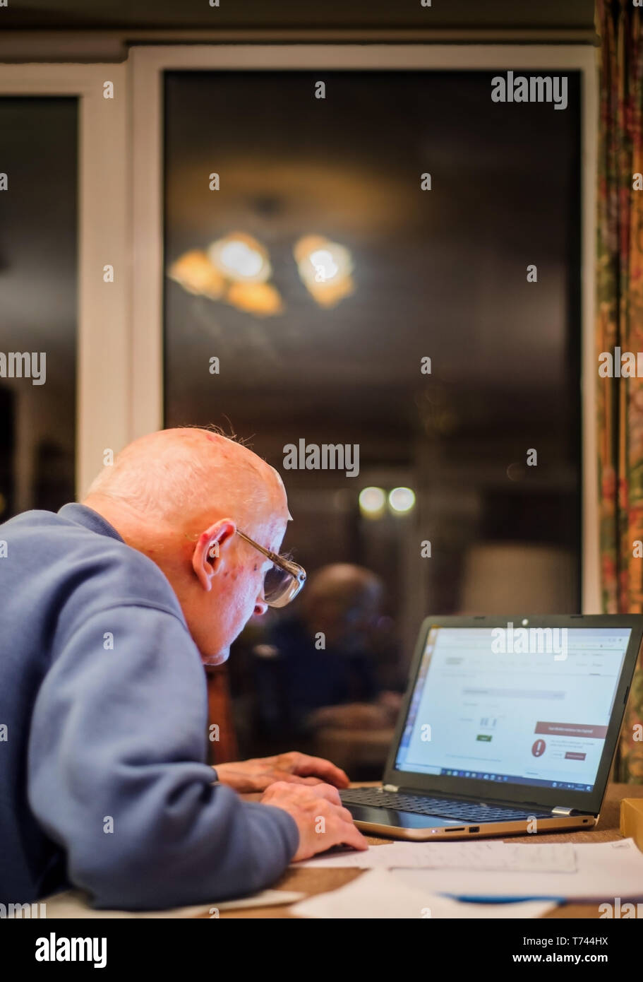 An old man of 93 years having trouble using his computer to check his finances online,very challenging for old people. Stock Photo