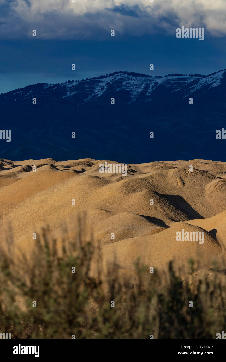 Sun and shade on sand/gravel quarry hills, with foothills and mountains in background Stock Photo
