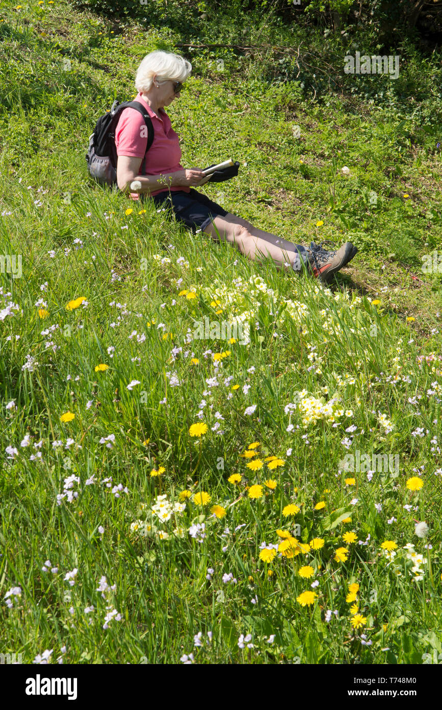 mature-woman-in-fifties-resting-while-taking-a-walk-in-wild-flowers