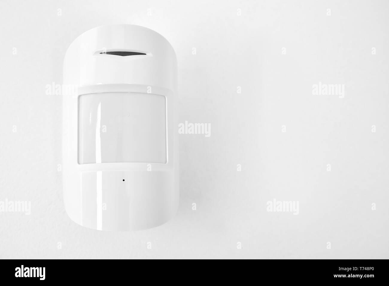 Modern motion sensor on wall indoors Stock Photo Alamy