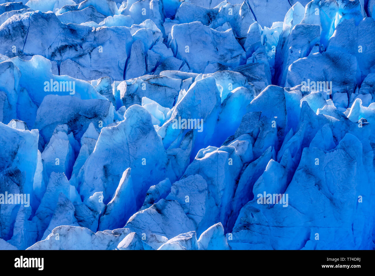 Blue glacial ice is exposed in crevasses on Hole in the Wall Glacier, Juneau Icefield, Tongass National Forest; Alaska, United States of America Stock Photo