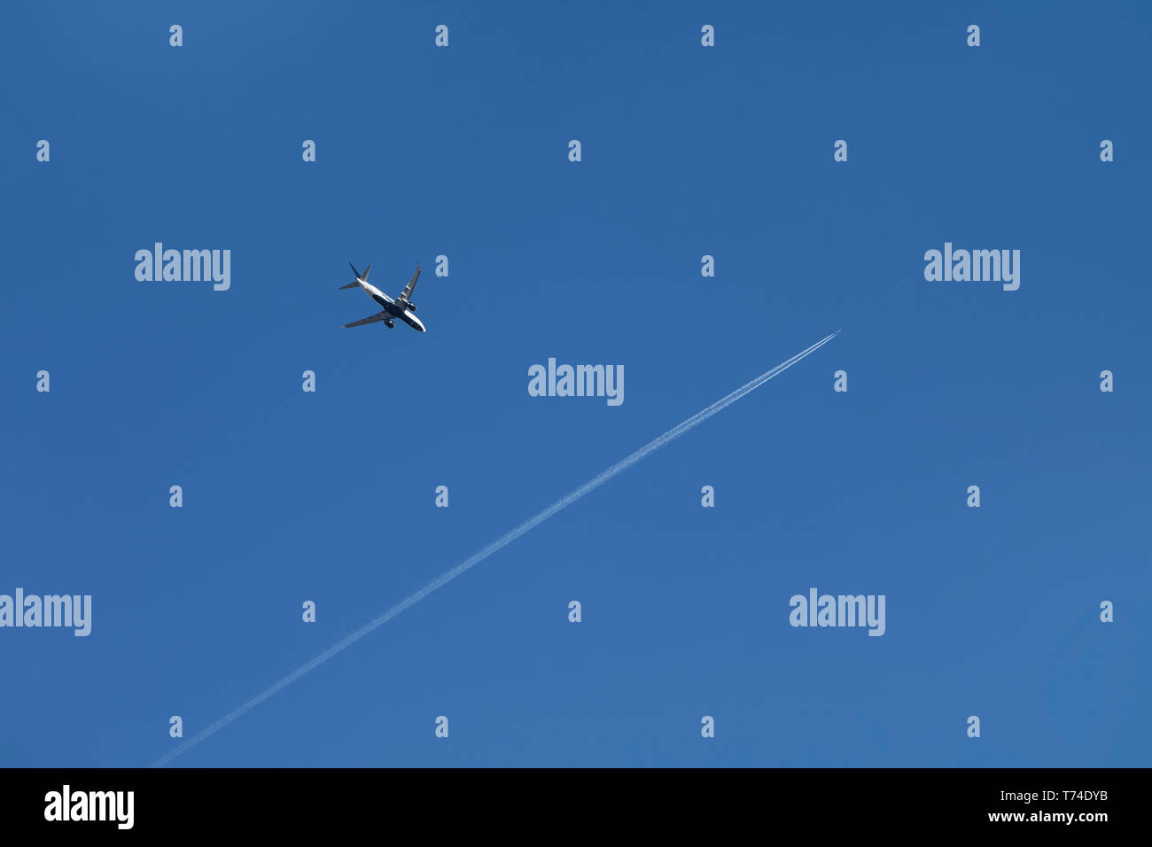 Commercial aircraft crossing paths over Halton Hills in a blue sky; Ontario, Canada Stock Photo