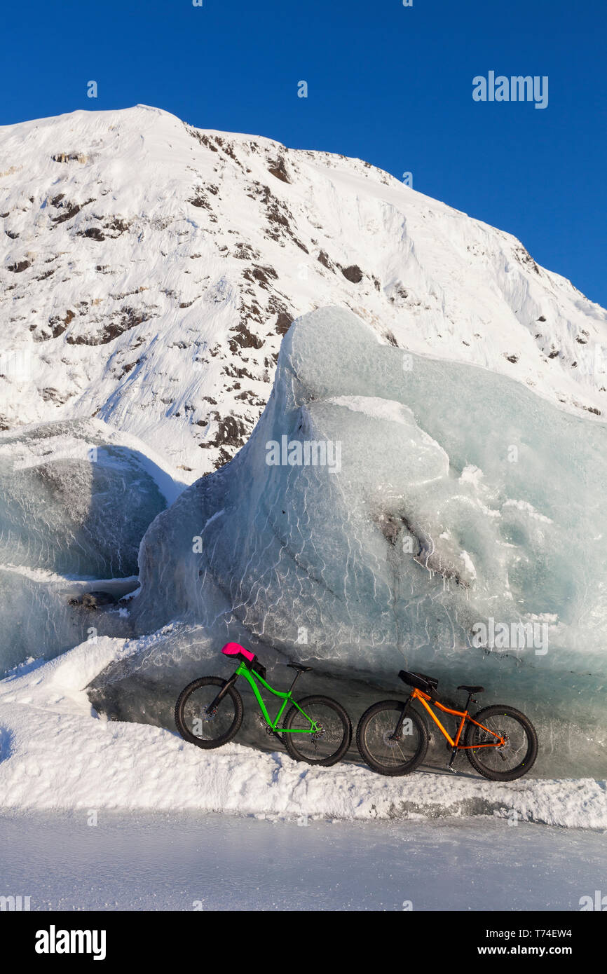 Fatbikes, 907 fat tire bike and Fatback fat tire bike, resting against giant iceberg in winter on Portage Lake, Chugach National Forest Stock Photo