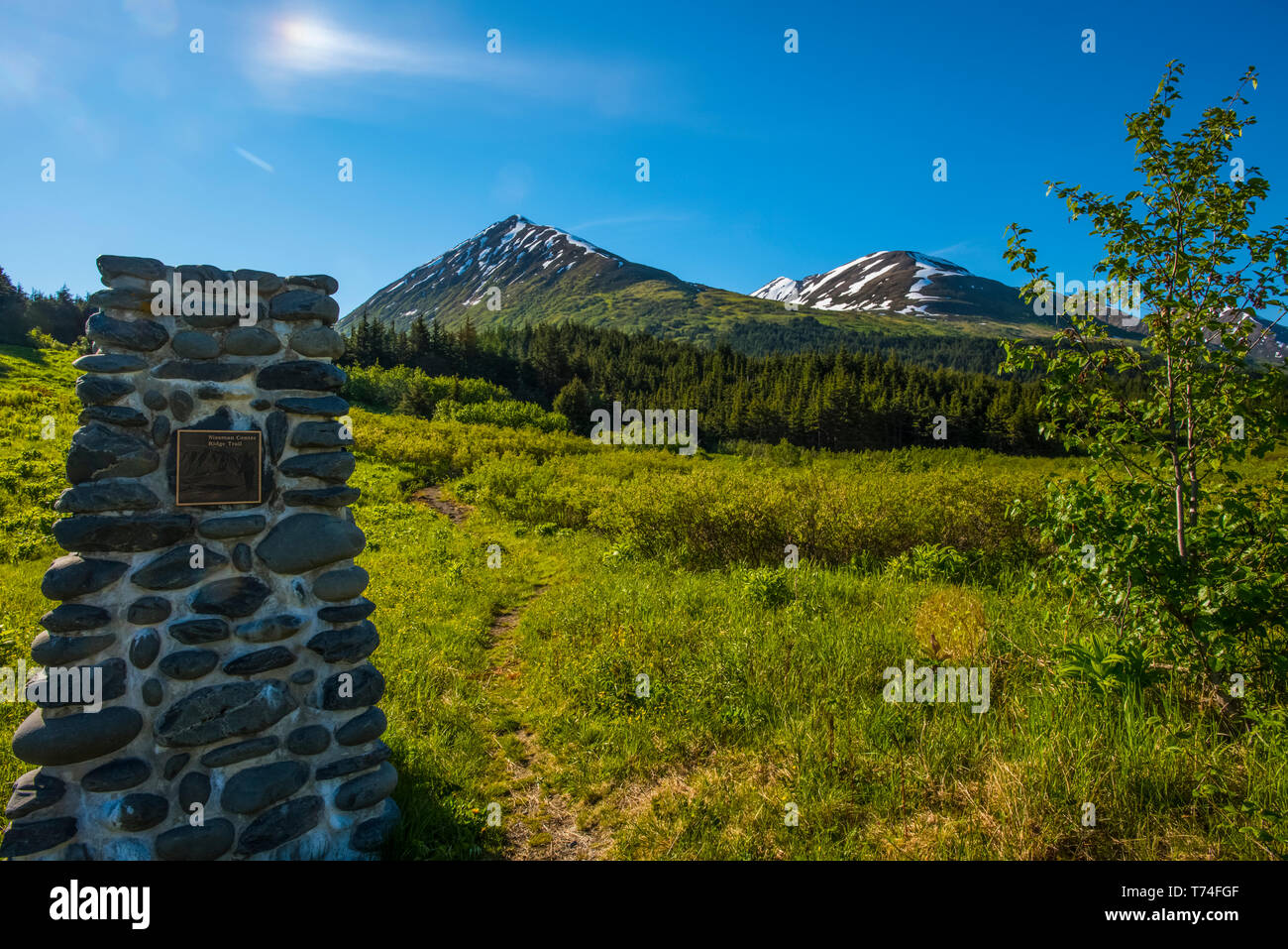 A stone monument marks the start of the Nissman Center Ridge Trail Head near Turnagain Pass Alaska on a sunny summer morning Stock Photo