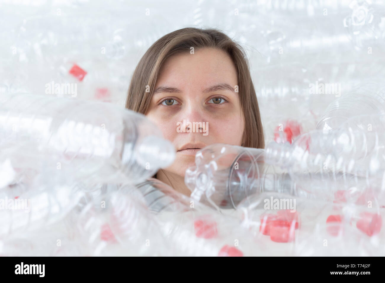 Environmental Protection, people and recyclable plastic concept - exhausted woman concerned with environment disaster sitting in a pile plastic bottle Stock Photo