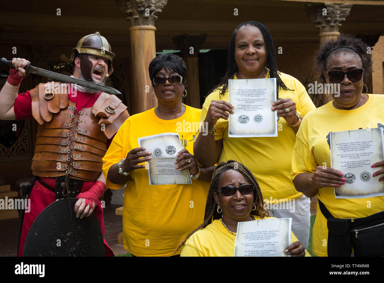 May 3, 2019 - Orlando, Florida, U.S - Women visiting from South Carolina pose for a group photo, holding certificates of completion, after participating in a Roman soldier training camp at The Holy Land Experience (HLE) in Orlando, Florida. The theme park, owned by the Trinity Broadcasting Network, recreates the architecture and themes of the ancient city of Jerusalem in 1st-century Judea. HLE is a non-denominational Christian living biblical museum and church. There are multiple religious-themed live performances given throughout the day in various locations, inside and out. (Credit Image: © Stock Photo