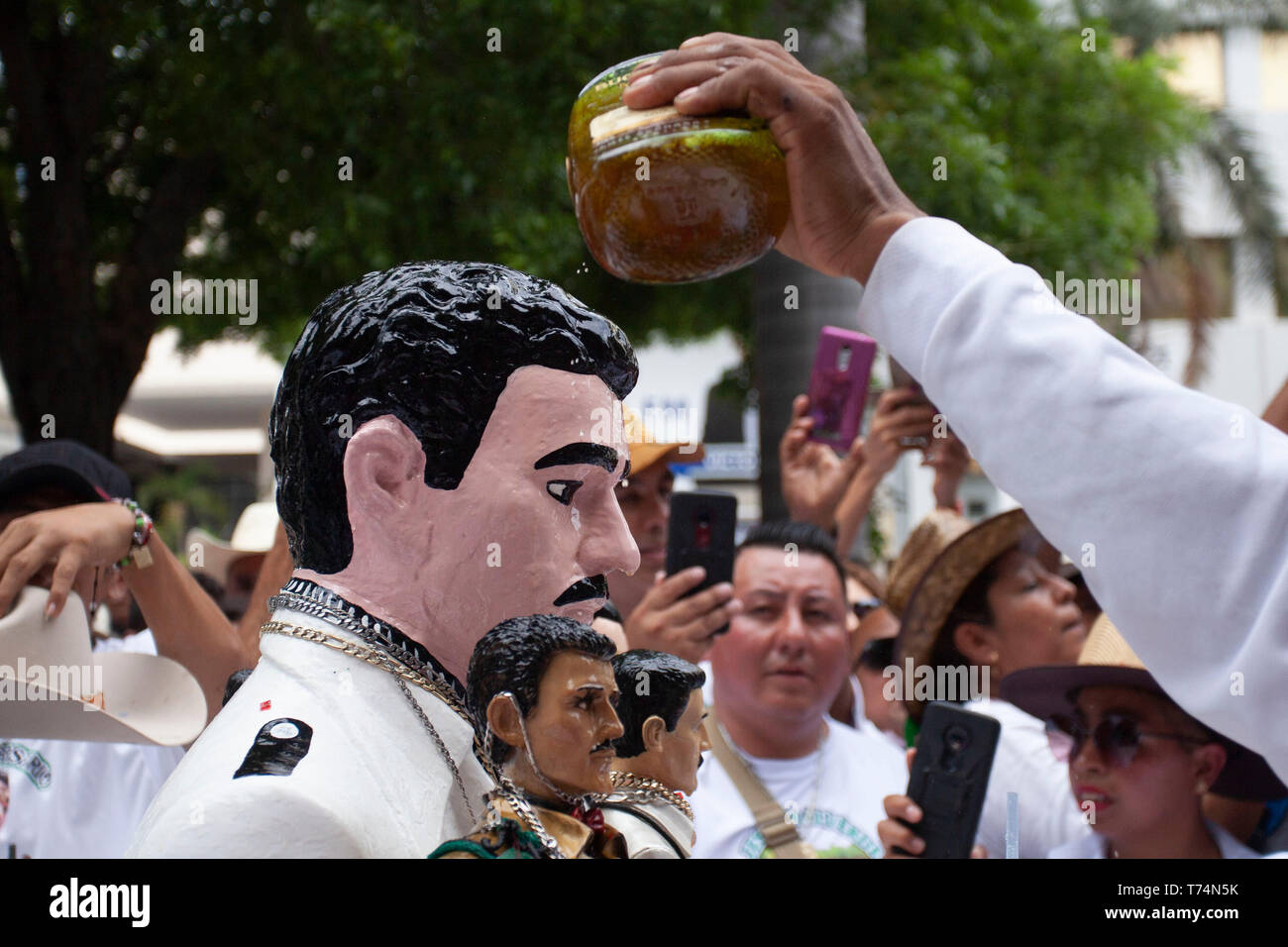Culiacan, Mexico. 03rd May, 2019. Believers pour whisky over the bust of Jesus Malverde, who is considered a saint of drug bosses in Mexico. On the occasion of his 110th anniversary of death on 03.05.2019 numerous faithful gathered in his native town in the federal state of Sinaloa. Malverde, who is not recognized as a saint by the Catholic Church, is said to have been a highwayman during his lifetime. Many Mexicans worship him as a kind of Robin Hood. According to oral tradition, he robbed the rich families in the Sinaloa region and then distributed the booty among the poor. Credit: dpa pictu Stock Photo