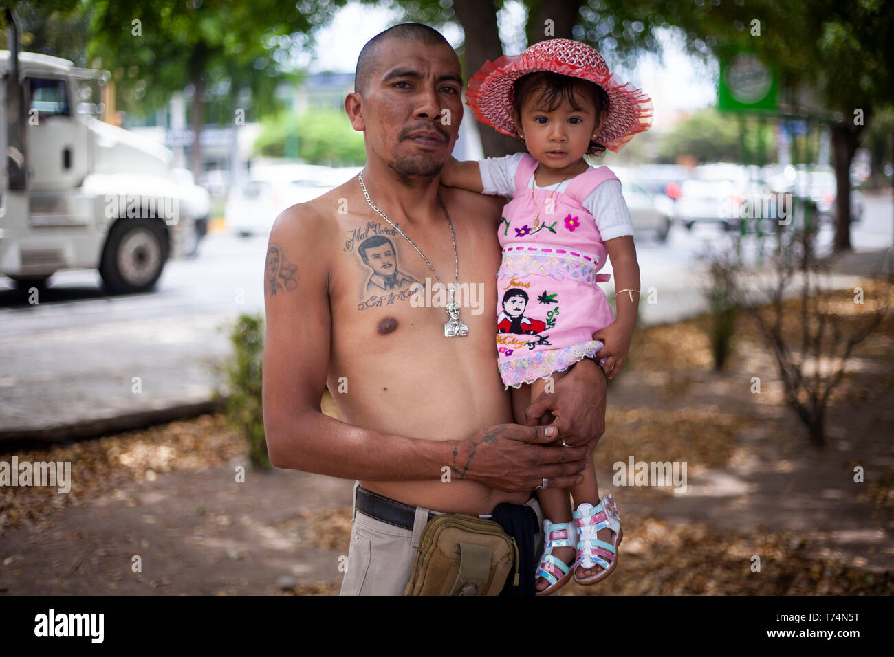 Culiacan, Mexico. 03rd May, 2019. Jose Luis holds his daughter Arely and has a tattoo of Jesus Malverde, who is considered a saint of drug bosses in Mexico. On the occasion of his 110th anniversary of death on 03.05.2019 numerous faithful gathered in his native town in the federal state of Sinaloa. Malverde, who is not recognized as a saint by the Catholic Church, is said to have been a highwayman during his lifetime. Many Mexicans worship him as a kind of Robin Hood. According to oral tradition, he robbed the rich families in the Sinaloa region and then distributed the booty among the poor. C Stock Photo