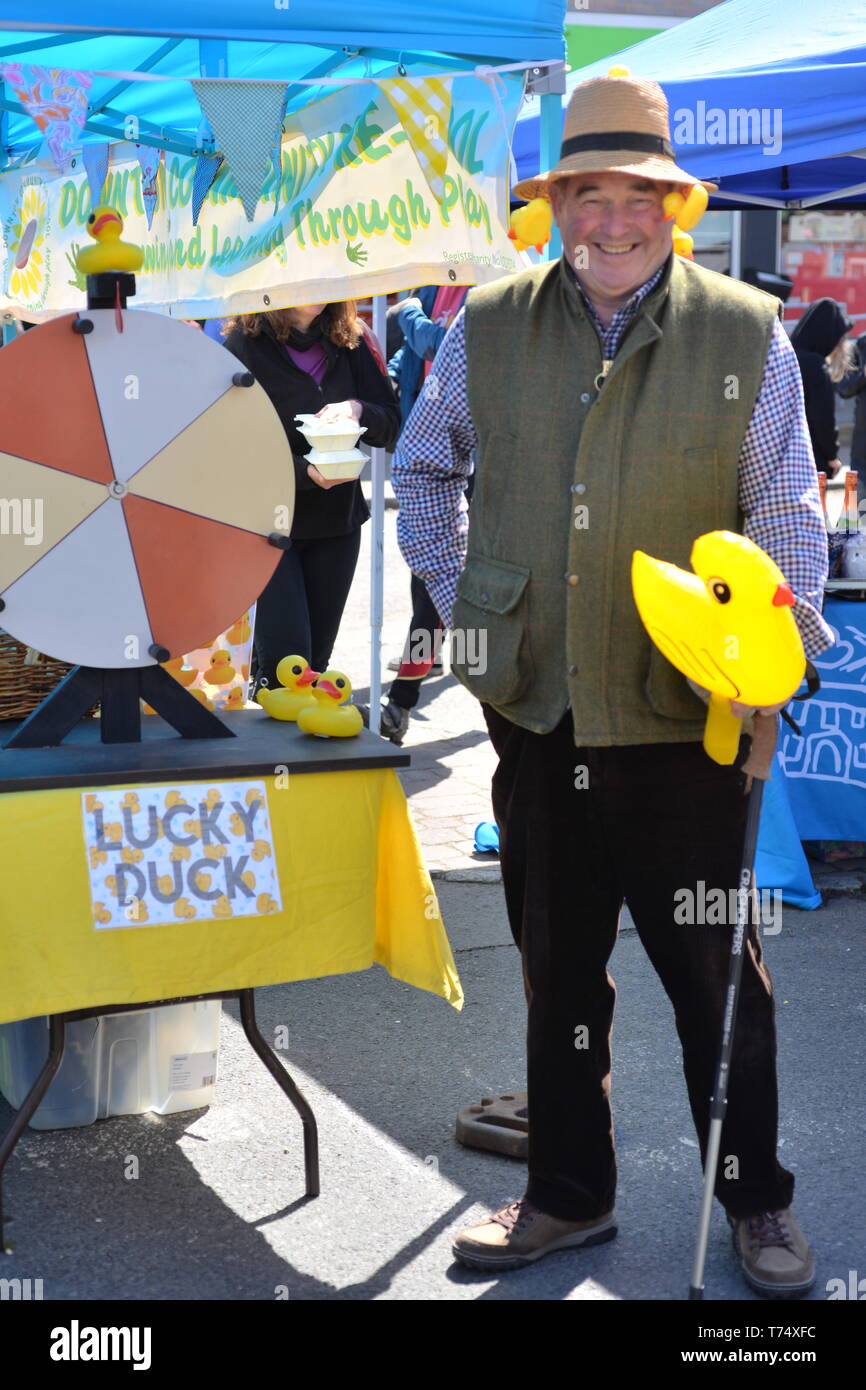 Duck race ticket vendor holding a yellow rubber duck at Downtown Cuckoo Fair near Salisbury, UK, May 4th, 2019,  The annual street fair takes place along The Borough in the South Wiltshire village. Stock Photo