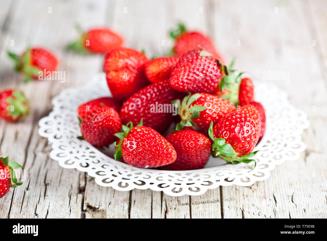 Fresh red strawberries on white plate on rustic wooden background ...