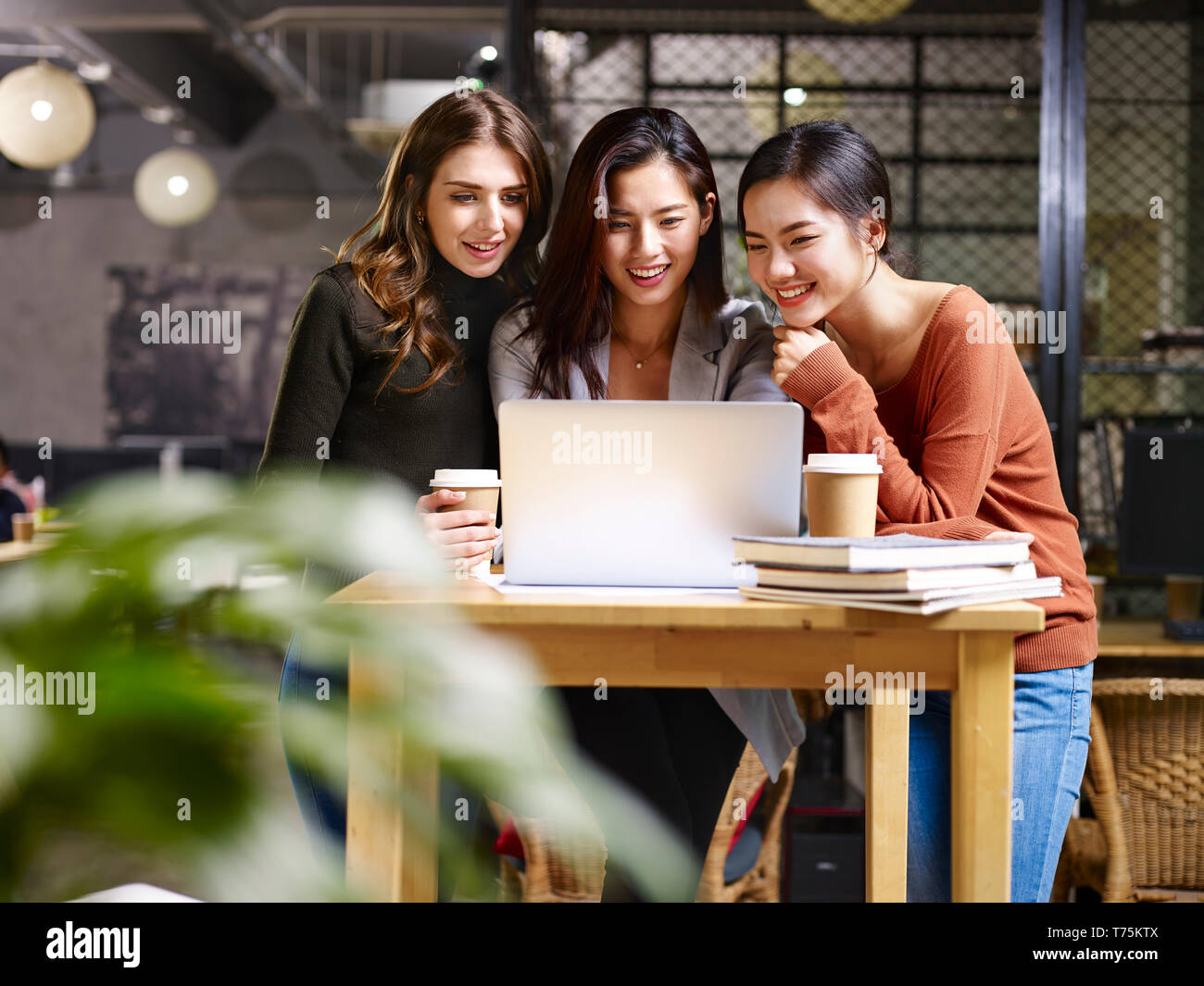 three happy businesswomen asian and caucasian using laptop computer together. Stock Photo
