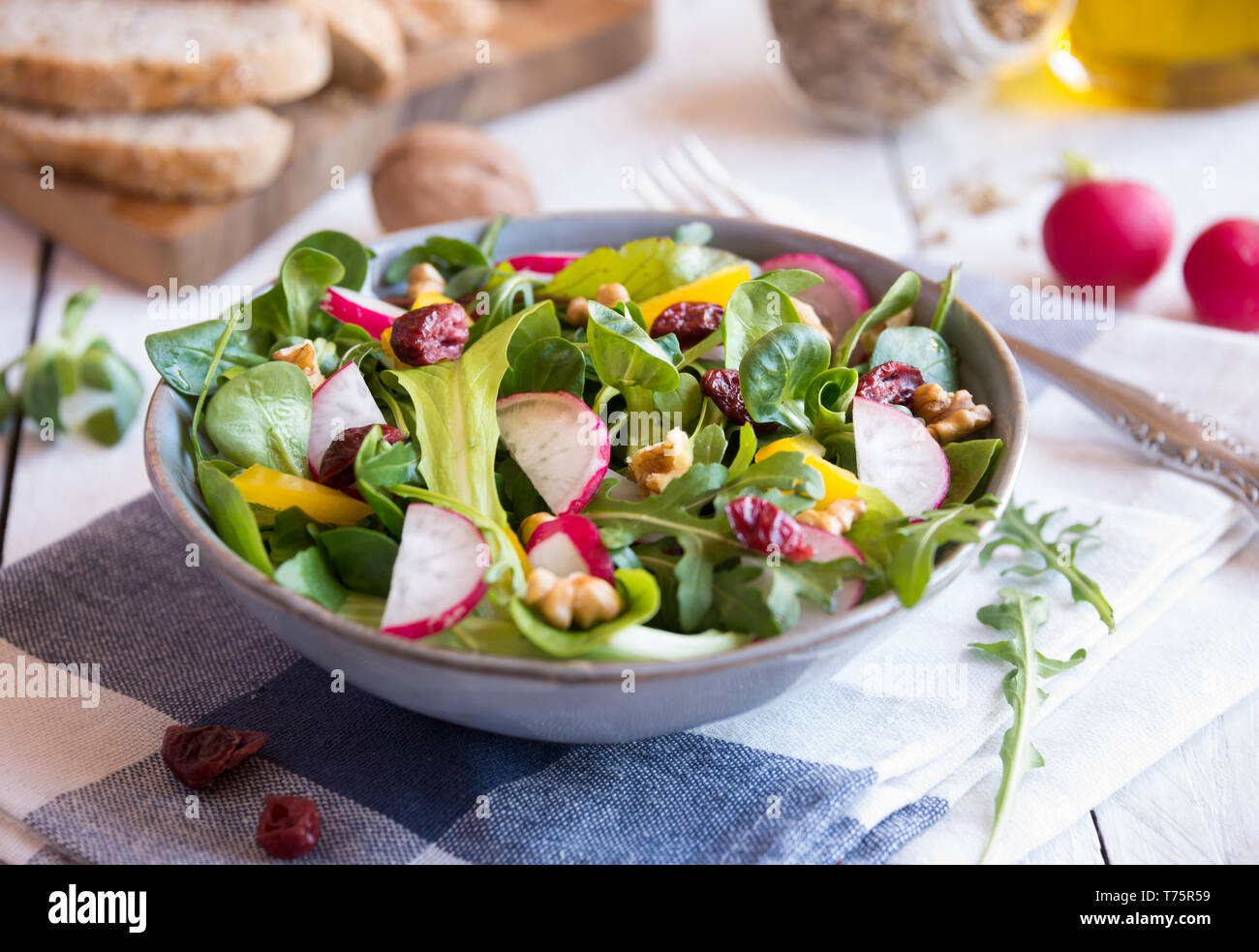 Fresh vegetable salad with radish, arugola, croutons in a bowl on white wood Stock Photo