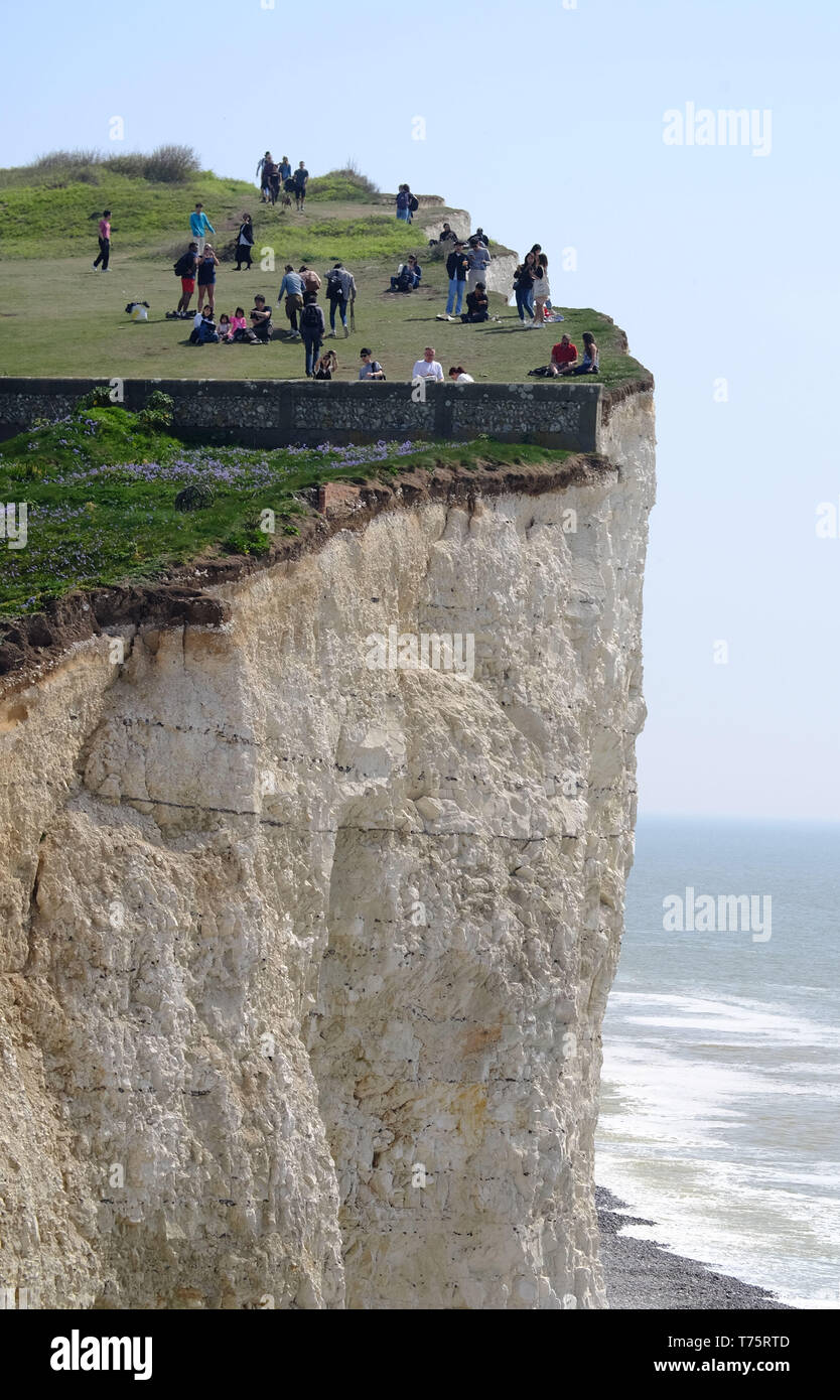 Tourists risking their lives to get selfies on 400 foot crumbling chalk cliffs, Birling Gap, East Sussex, UK Stock Photo