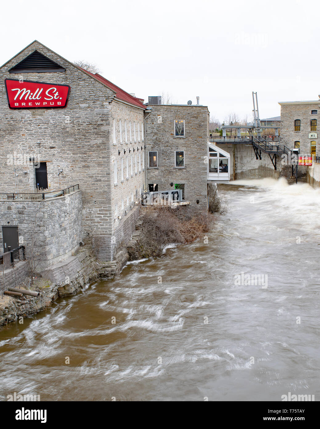 Extreme flooding of the Ottawa River in April 2019 forced Hydro Ottawa floodgates to be opened just above the Mill Street Pub near Chaudiere Falls. Stock Photo