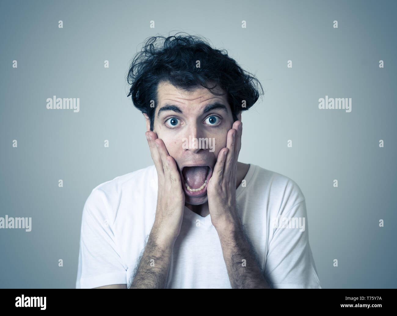 Close up portrait of funny young man looking embarrassed feeling ashamed and shy isolated against neutral background in People, human emotions and exp Stock Photo