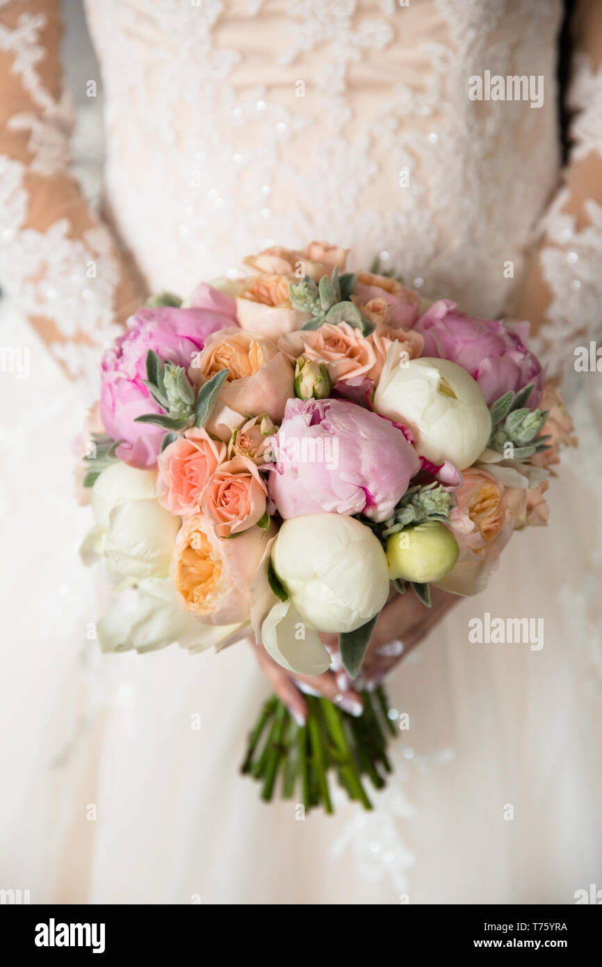 Wedding bouquet of roses and peonies in the hands of an unrecognizable ...
