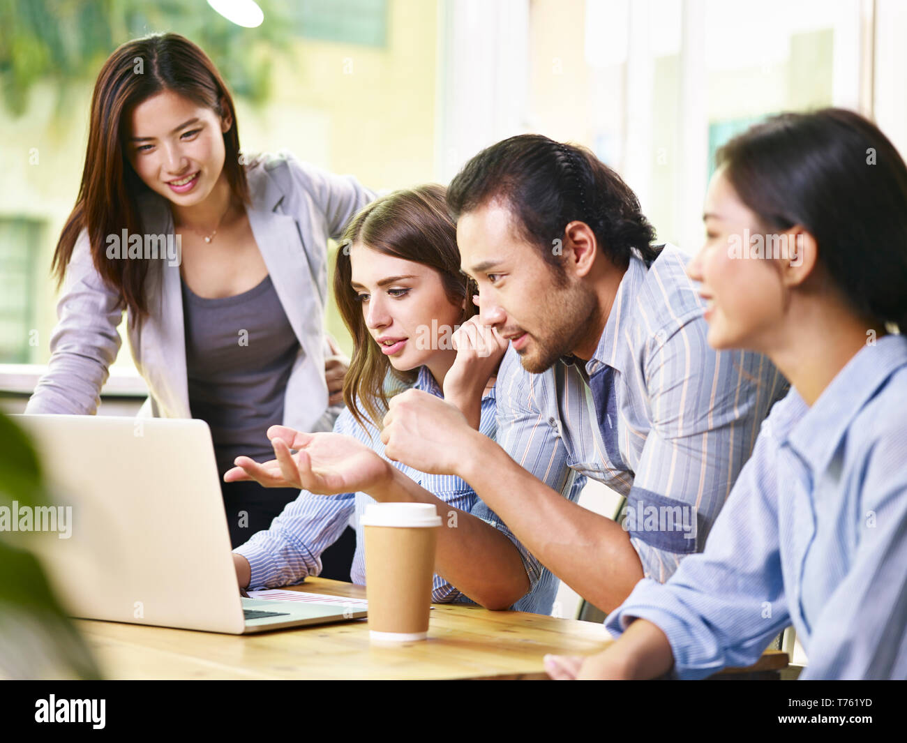 team of four business people meeting in office using laptop computer. Stock Photo