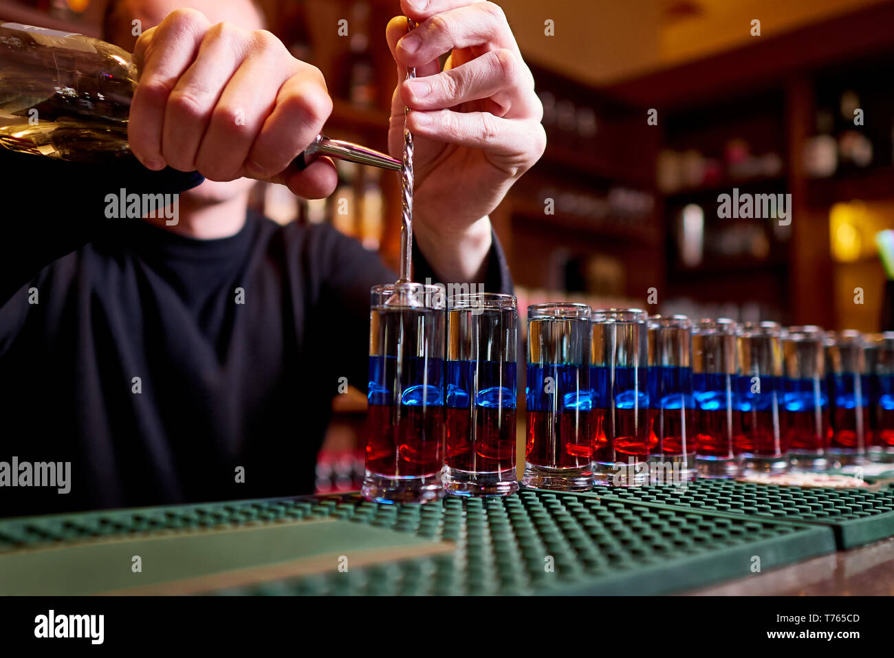 Alcoholic shots on bar counter. Professional bartender pours alcoholic