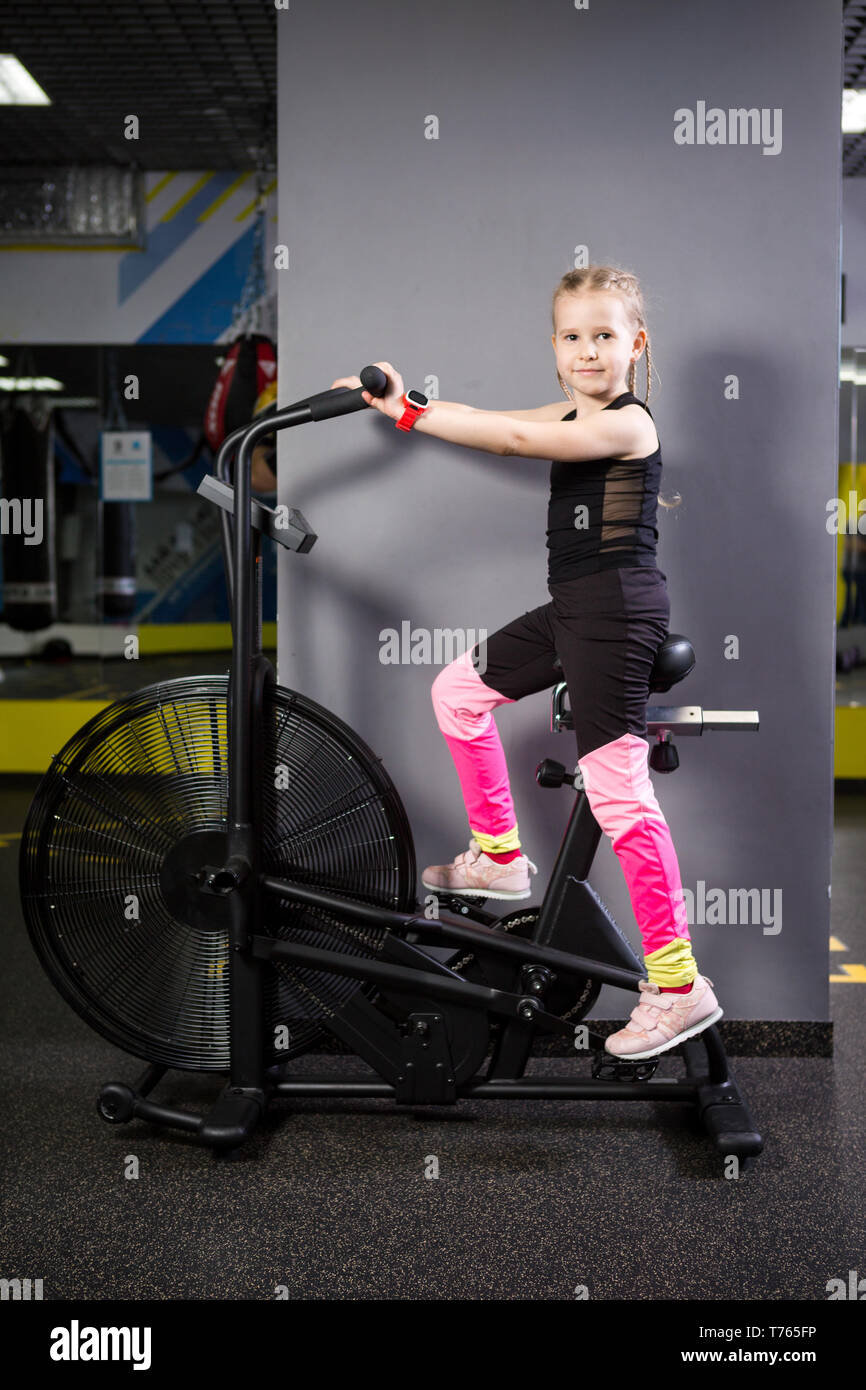 Cancelar cinturón cosecha Small attractive caucasian child using exercise bike in the gym. Fitness. A  little athlete using an air bike for a cardio workout at the crossfit gym  Stock Photo - Alamy