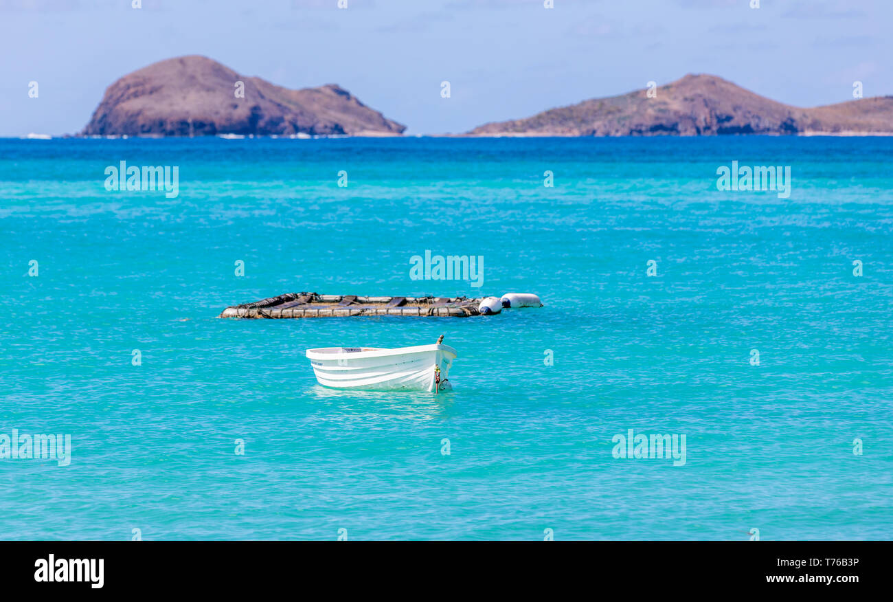 small white boat sitting in a blue sea Stock Photo