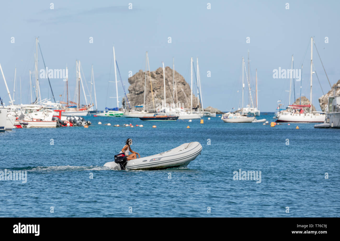 tan woman operating a inflatable tender in St Barts Stock Photo