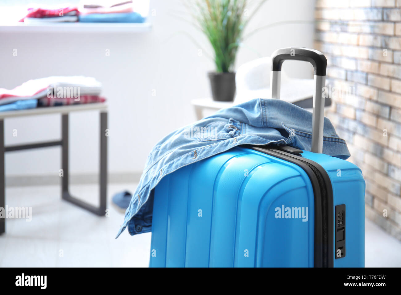Packed suitcase and denim jacket in room Stock Photo Alamy