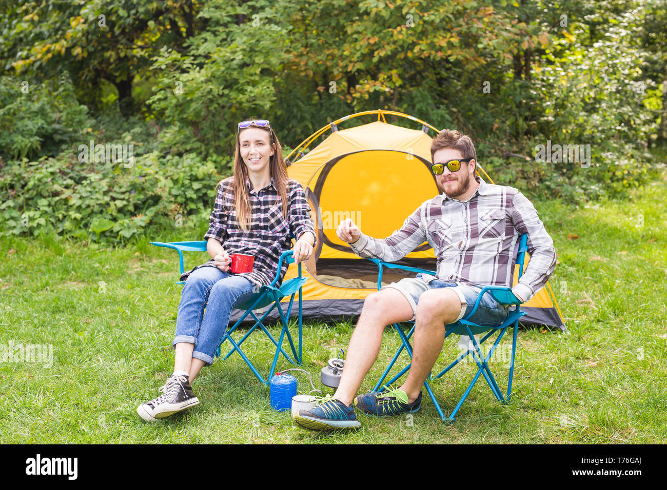 people, summer tourism and nature concept - young couple sitting near a ...