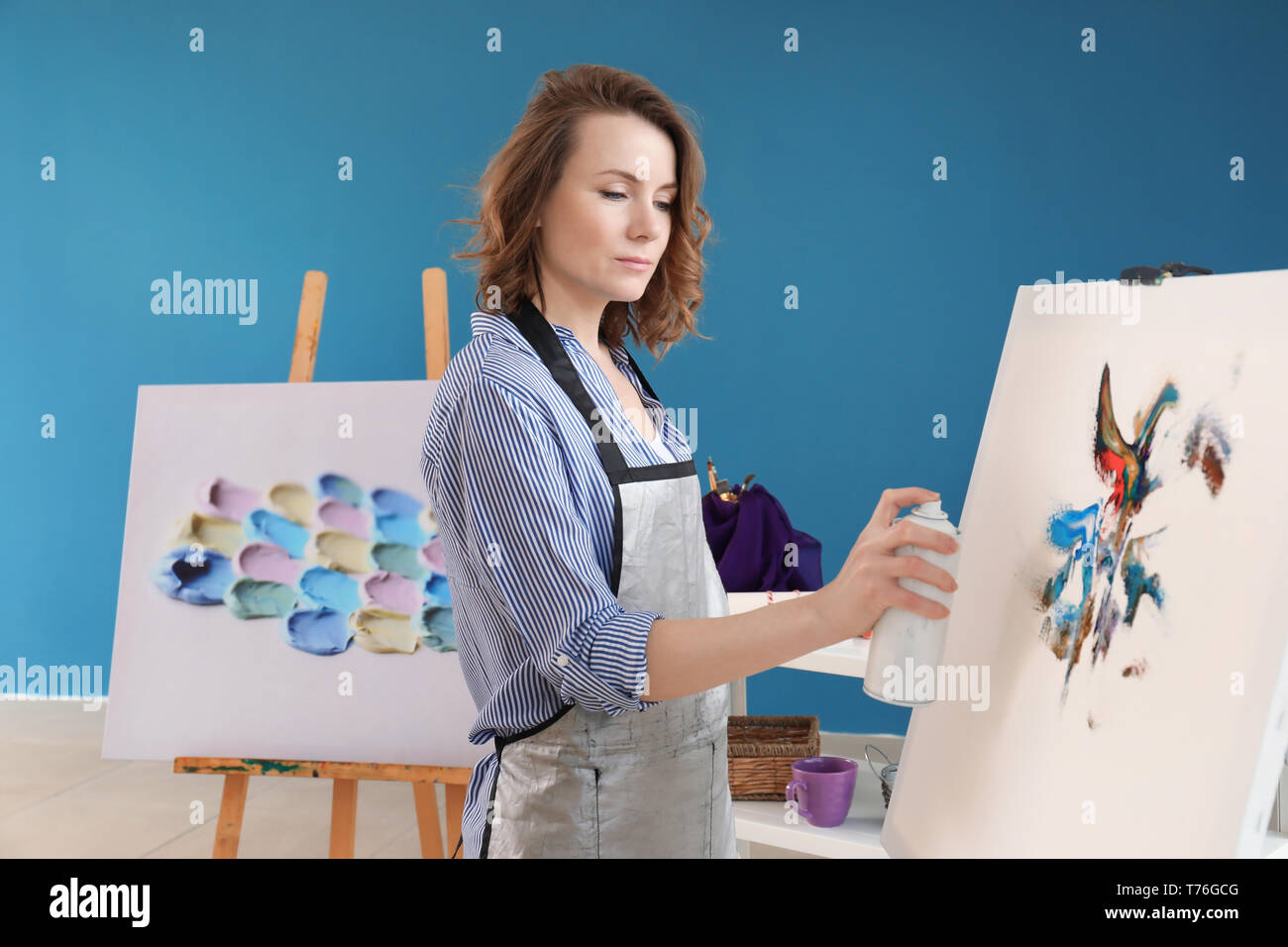 Female artist painting with aerosol spray in workshop Stock Photo - Alamy